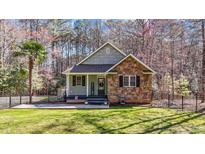 Charming single-Gathering home boasts a welcoming front porch, stone accents, and well-manicured lawn at 113 Pony Dr, Louisburg, NC 27549