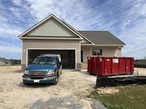 New construction home with attached garage and a large red dumpster in the front yard at 163 Royal Ave, Selma, NC 27576