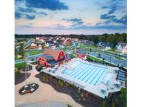 An aerial view of a community pool, barn-themed clubhouse, lounge chairs, and neighborhood homes at 217 Inspiration Way Way, Fuquay Varina, NC 27526