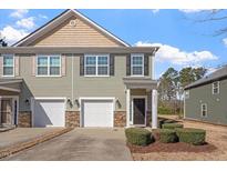 Charming townhouse with attached garages, lush landscaping, and a welcoming entrance on a sunny day at 2306 Stoney Spring Dr, Raleigh, NC 27610
