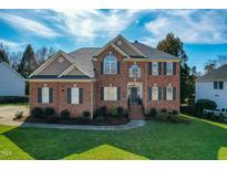 Two-story brick home featuring a manicured lawn, classic architectural details, and beautiful landscaping at 2720 Stratford Hall Dr, Raleigh, NC 27614