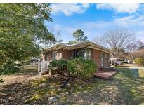 Cozy brick home with a well-maintained lawn and mature trees surrounding the property at 2911 Broad St, Durham, NC 27704