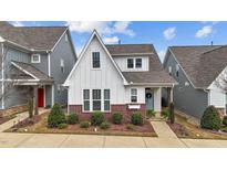 Charming two-story home featuring white siding, brick accents, and landscaped front yard at 308 Masden Rd, Holly Springs, NC 27540