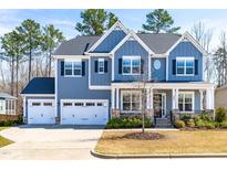 Beautiful two-story home with a three-car garage and a well-manicured lawn at 409 Tintern Ln, Apex, NC 27523