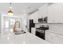 Bright kitchen features white cabinets, stainless steel appliances, subway tile backsplash and large island at 6434 Astor Elgin St, Raleigh, NC 27616
