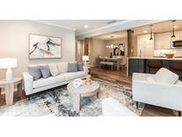 Inviting living room with a stylish sofa, modern artwork, and seamless flow into the dining and kitchen areas at 700 Bishops Park Dr # 205, Raleigh, NC 27605