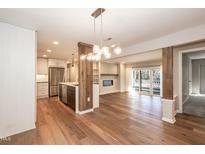 Open-concept living space with hardwood floors, modern lighting, fireplace, and kitchen view at 700 Bishops Park Dr # 205, Raleigh, NC 27605