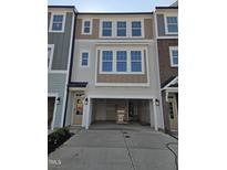 Charming townhome featuring a spacious garage, light gray siding, and large windows for abundant natural light at 10004 Secluded Garden Drive Rd # 180, Apex, NC 27523
