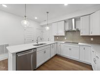 Bright kitchen with stainless steel dishwasher, white cabinets, stylish pendants, and island at 1230 Coach Station Alley # 101, Raleigh, NC 27601