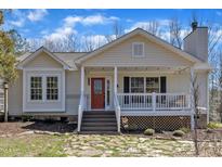 Charming single-story home featuring a covered front porch, red door, stone pathway, and cozy cottage style at 1384 Sims Bridge Rd, Kittrell, NC 27544