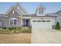 Charming home featuring stone accents, a two-car garage, and well-maintained landscaping at 157 Auburn Village Blvd, Raleigh, NC 27610