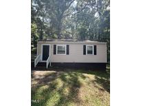Charming one-story home featuring black shutters, a black door, and light siding nestled among mature trees at 158 Torain St, Hillsborough, NC 27278