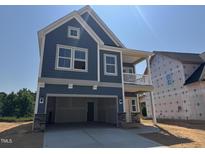 Two-story blue home with stone accents, an attached garage, and a second-story balcony at 247 Meadowbark Bnd # 29, Garner, NC 27529