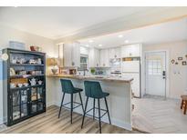 Bright kitchen features a breakfast bar, white cabinetry, and light wood-look flooring at 2968 Tram Rd, Fuquay Varina, NC 27526