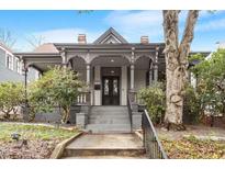 Charming historic home featuring a covered porch with detailed columns and inviting entryway, landscaping, and mature trees at 321 E Lane St, Raleigh, NC 27601