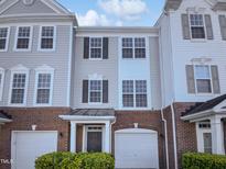 Charming townhouse featuring a two-car garage, red brick base, and light gray siding at 4842 Wyatt Brook Way, Raleigh, NC 27609