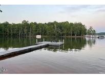 Lakefront view featuring a dock and seating area on the water with treeline in the background at 55 Waters Edge Loop, Henderson, NC 27537