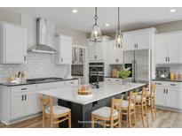 Bright kitchen with an island with chairs, stainless steel appliances, pendant lights, and white cabinets at 69 Alex Farm Ct # 21, Zebulon, NC 27597