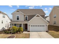 Charming two-story home featuring a tan exterior, two-car garage, and landscaped front yard at 717 Tailrace Falls Ct, Wake Forest, NC 27587