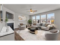 Bright living room with large windows, fireplace, ceiling fan, neutral tones and stylish décor at 717 Tailrace Falls Ct, Wake Forest, NC 27587