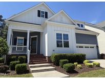 Charming home with white siding, covered porch, manicured landscaping, and attached two-car garage at 1564 Highpoint St, Wake Forest, NC 27587