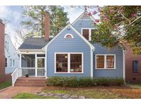 Charming blue two-story home featuring a brick chimney, a screened-in porch, and beautiful landscaping at 205 W Markham Ave, Durham, NC 27701