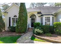 Charming home featuring a stone walkway leading to an arched doorway and lush, manicured landscaping at 218 Whisperwood Dr, Cary, NC 27518