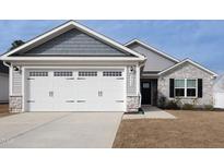 Attached two car garage with white door and stone veneer base on a home with gray siding at 8630 Kenridge Ln, Fuquay Varina, NC 27526