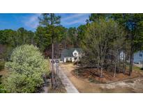Charming two-story home surrounded by lush greenery and a long driveway at 902 Loop Rd, Clayton, NC 27527