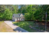 Charming home featuring lush landscaping, a well-maintained lawn, and an American flag waving in the yard at 902 Loop Rd, Clayton, NC 27527