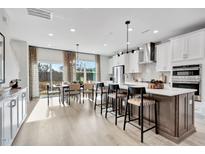 Open-concept kitchen with white cabinets, stainless steel appliances, and a dining area with natural light at 10006 Secluded Garden Drive Rd # 181, Apex, NC 27523