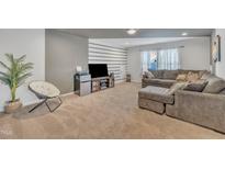 Inviting living room featuring a plush gray sectional sofa and horizontal striped accent wall at 123 Carbone Ln, Clayton, NC 27527
