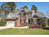 Charming two-story brick home with well-manicured lawn and mature trees, offering classic curb appeal at 12404 Brandon Hall Dr, Raleigh, NC 27614
