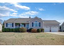 Charming single-story home featuring a two-car garage, porch, and a well-maintained front yard with landscaped bushes at 131 Woodglen Dr, Clayton, NC 27527