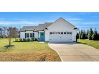 Charming single-story home featuring a two-car garage, bright blue door, and well-maintained landscaping at 28 Sandcastle Ln, Four Oaks, NC 27524