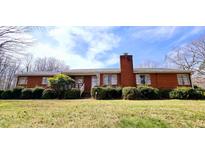 Charming red brick home featuring mature landscaping, a brick chimney, and a well-manicured front yard at 3015 Nc Hwy 87 South, Graham, NC 27253
