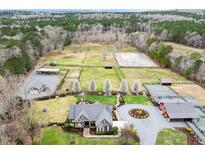 Stunning aerial view of an estate with horse pastures, riding arena, and well-manicured grounds at 3417 Pea Ridge Rd, New Hill, NC 27562