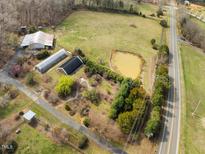 Expansive aerial view featuring a barn, greenhouses, pond, and surrounding lush greenery at 4811 New Sharon Church Rd, Hillsborough, NC 27278
