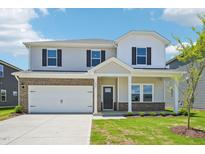 Two-story home featuring a spacious two car garage and a welcoming front porch at 571 White Birch Ln, Angier, NC 27501