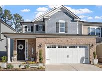 Charming two-story home featuring a brick facade, a two-car garage, and a welcoming front porch with decorative wreath at 938 Haybeck Ln, Apex, NC 27523