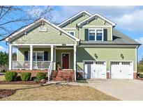 Charming two-story home with a welcoming porch and a two-car garage in a manicured front yard at 1024 Jensen Grove Ct, Fuquay Varina, NC 27526