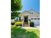 Charming home featuring a covered porch, brick steps, stone accents, and a well-manicured lawn under a clear blue sky at 105 Olde Liberty Dr, Youngsville, NC 27596