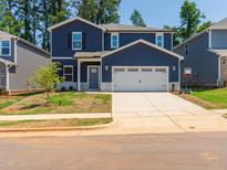 Two-story home with blue siding, white trim, two-car garage, and a freshly seeded front yard at 153 Klamath Dr, Garner, NC 27529