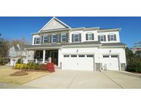 Stunning two-story home featuring a stone and white facade, three-car garage, and well-manicured landscaping at 1532 Champlain Crest Way, Cary, NC 27513