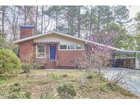 Quaint single-story brick home with a carport, chimney, and blossoming tree in the front yard at 2208 Tampa Ave, Durham, NC 27705
