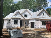 New construction home with building wrap and lumber on the lot at 249 High Ridge Ln, Pittsboro, NC 27312