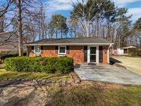 Brick single-story home with a trimmed front hedge, shutters, and a light-colored front porch at 317 Gary St, Raleigh, NC 27606