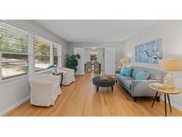 Bright living room with hardwood floors, a gray couch, and large windows that let in natural light at 3605 Octavia St, Raleigh, NC 27606