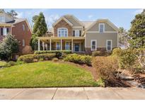Charming home featuring a welcoming front porch, manicured lawn, and a mix of stone and siding accents at 921 Alden Bridge Dr, Cary, NC 27519