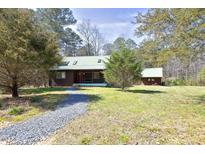 Inviting exterior showcasing a charming home, green roof, and mature trees on a sprawling lawn at 9511 Collins Creek Dr, Chapel Hill, NC 27516